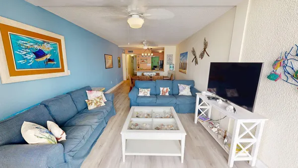 a living room with furniture a flat screen tv and a wall painting