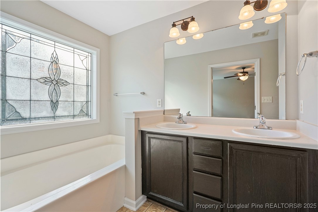 720 Cape Fear Road Raeford, NC 28376 - Photo 26 of 35 a bathroom with a double vanity sink a large mirror and a bathtub