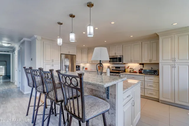 a kitchen with stainless steel appliances kitchen island granite countertop a table chairs and a refrigerator