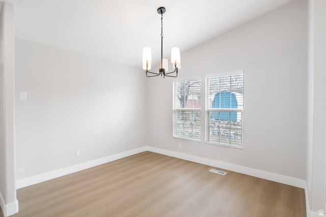 332 Hillgate Way Layton, UT 84041 - Photo 7 of 26 Empty room featuring wood finished floors, vaulted ceiling, and a chandelier