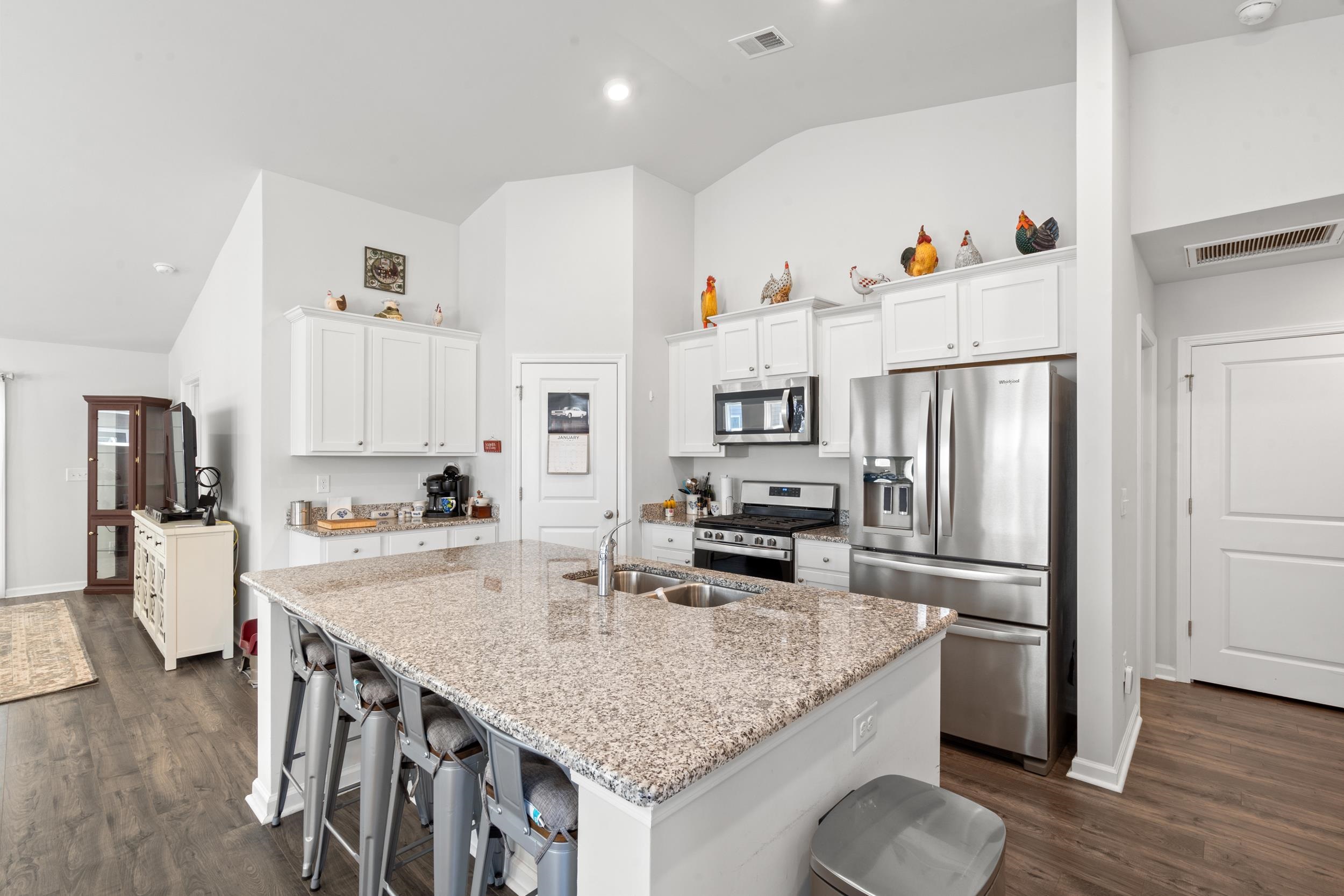 1404 Jardine Loop Little River, SC 29566 - Photo 22 of 31 Kitchen with white cabinets, stainless steel appliances, a breakfast bar, a kitchen island with sink, and light stone counters