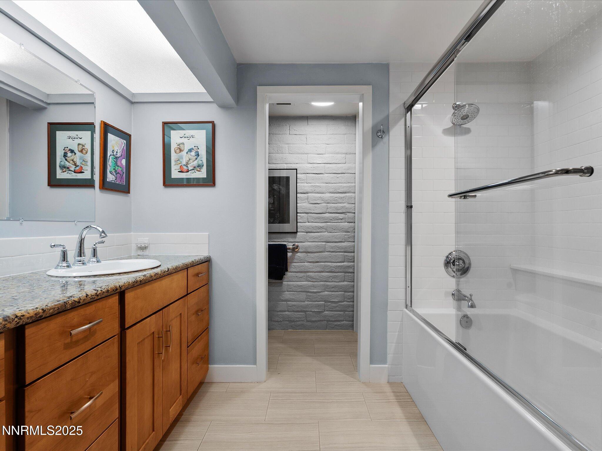 1200 Riverside Drive, Unit 1276 Reno, NV 89503 - Photo 31 of 47 a bathroom with a granite countertop sink a mirror a bathtub and shower