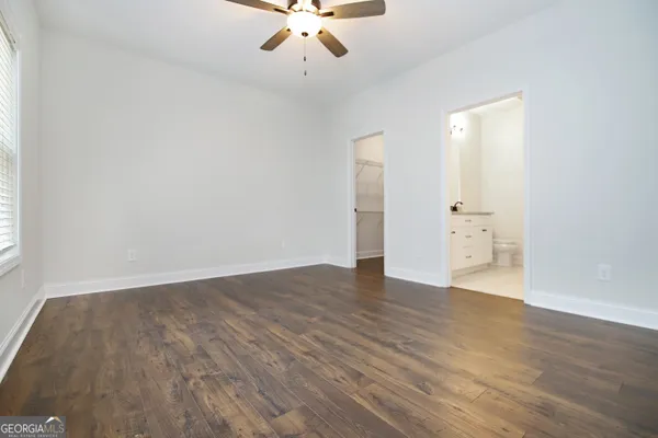 an empty room with wooden floor and ceiling fan