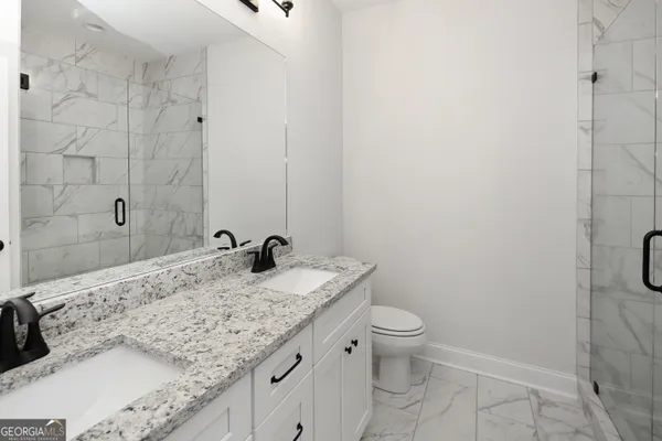 a bathroom with a granite countertop sink a toilet and a shower
