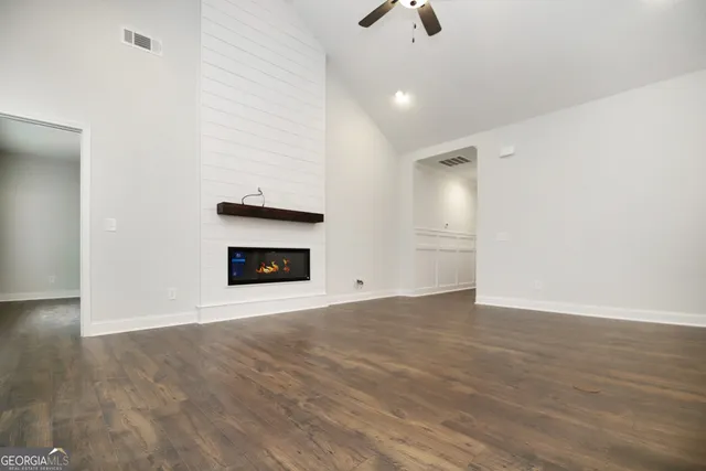 an empty room with wooden floor fireplace and windows