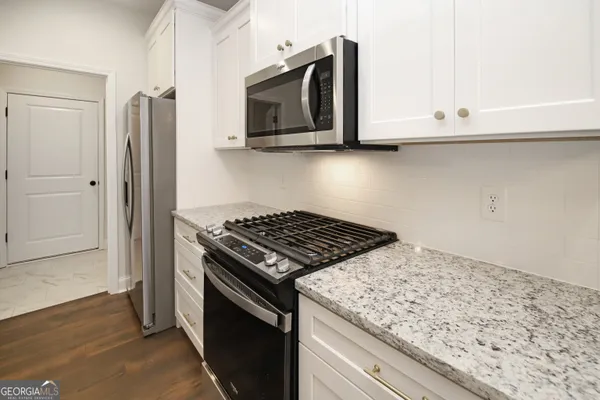 a kitchen with granite countertop cabinets stainless steel appliances and wooden floor