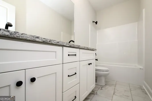 a bathroom with a granite countertop sink a toilet and vanity