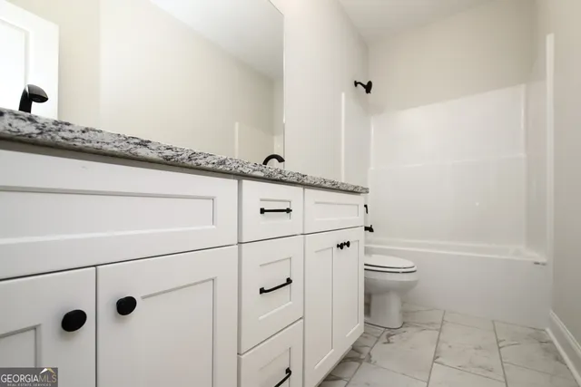 a bathroom with a granite countertop sink a toilet and vanity
