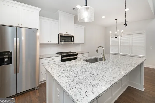 a kitchen with stainless steel appliances granite countertop a sink refrigerator and microwave