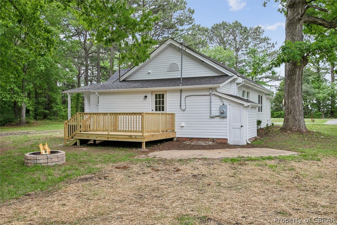 8213 Croaker Road Williamsburg, VA 23188 - Photo 35 of 50 Back of property with an outdoor fire pit, a wooden deck, and a lawn