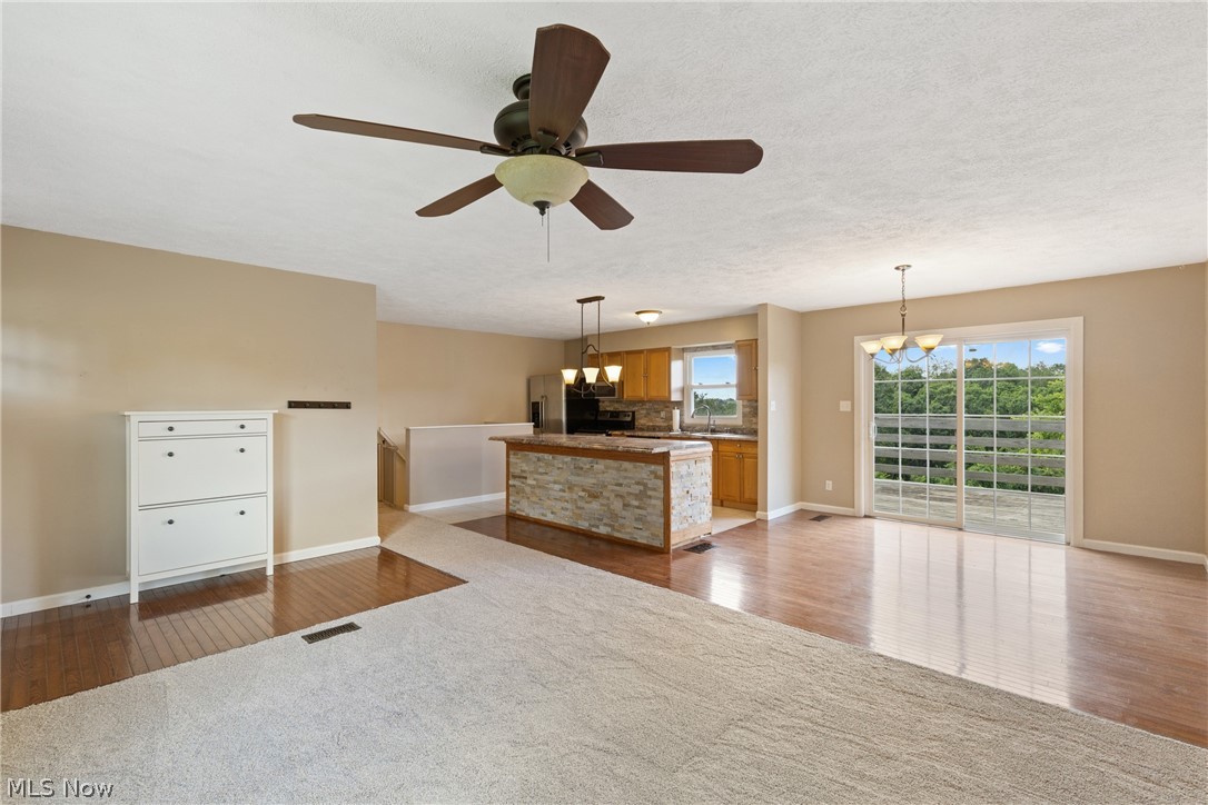 54131 Key Bellaire Road Bellaire, OH 43906 - Photo 16 of 36 Unfurnished living room featuring ceiling fan with notable chandelier, light hardwood / wood-style floors, and sink
