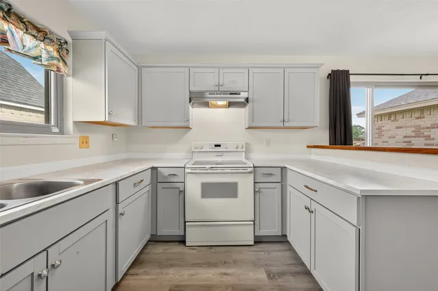 a white kitchen with stainless steel appliances granite countertop a sink and dishwasher a stove top oven with white cabinets