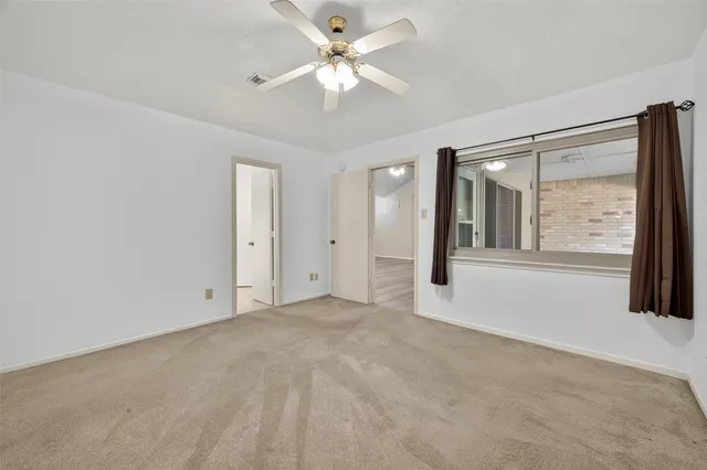 a view of a big room with windows and chandelier fan