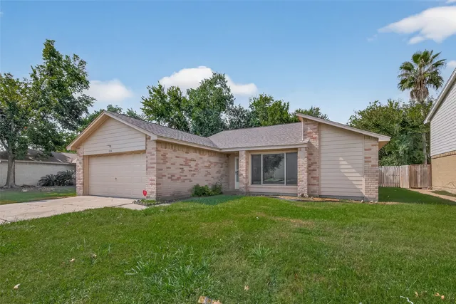 a view of a house with a yard and large tree