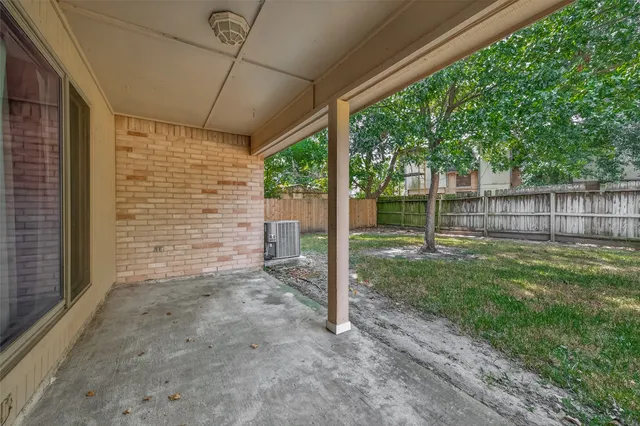 a view of a backyard with large trees and wooden fence