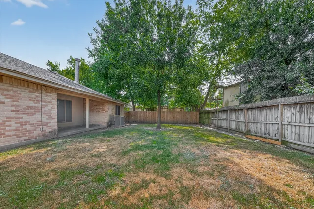 a view of a backyard with large trees and wooden fence