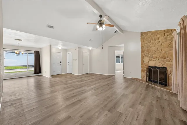 an empty room with wooden floor fireplace and windows