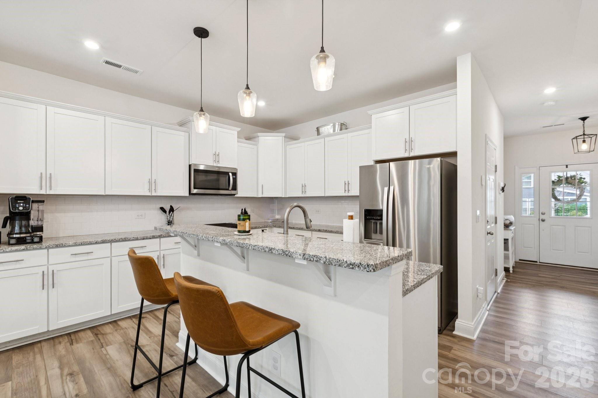 2081 Suttonview Road Fort Mill, SC 29708 - Photo 5 of 33 a kitchen with stainless steel appliances granite countertop a refrigerator a sink dishwasher a stove and white cabinets with wooden floor