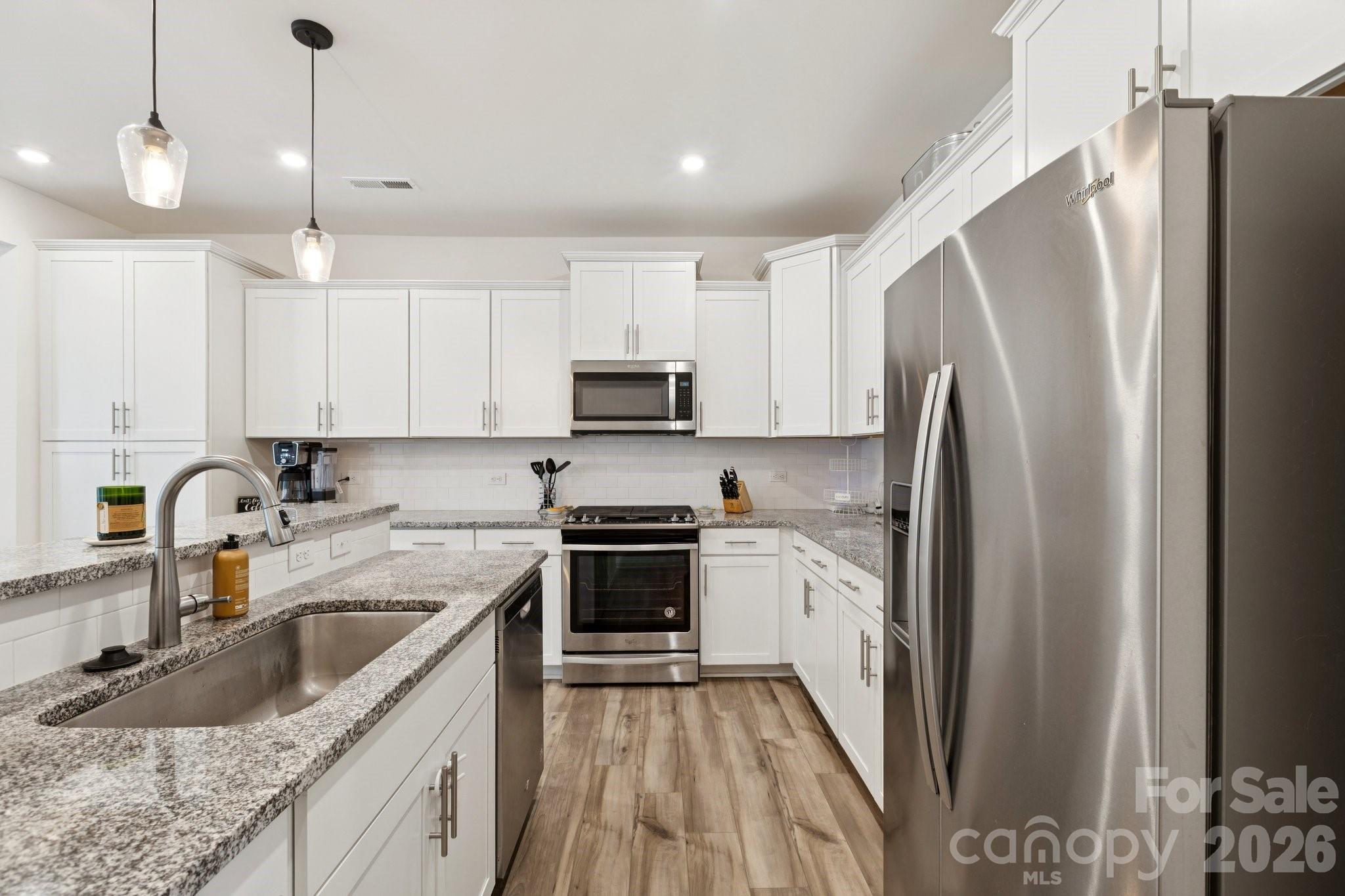 2081 Suttonview Road Fort Mill, SC 29708 - Photo 6 of 33 a kitchen with stainless steel appliances granite countertop a sink stove a refrigerator and a granite counter tops with white cabinets