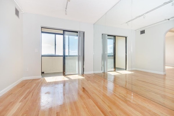 1731 Beacon Street, Unit 1110 Brookline, MA 02445 - Photo 4 of 24 an empty room with wooden floor and windows