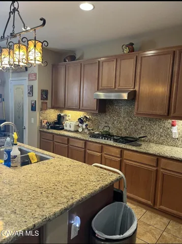 a kitchen with granite countertop a sink a stove and cabinets