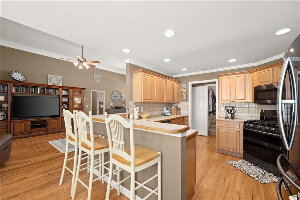 745 Roland Manor Drive Dacula, GA 30019 - Photo 15 of 63 a kitchen with stainless steel appliances kitchen island granite countertop a stove top oven a sink a dining table and chairs with wooden floor