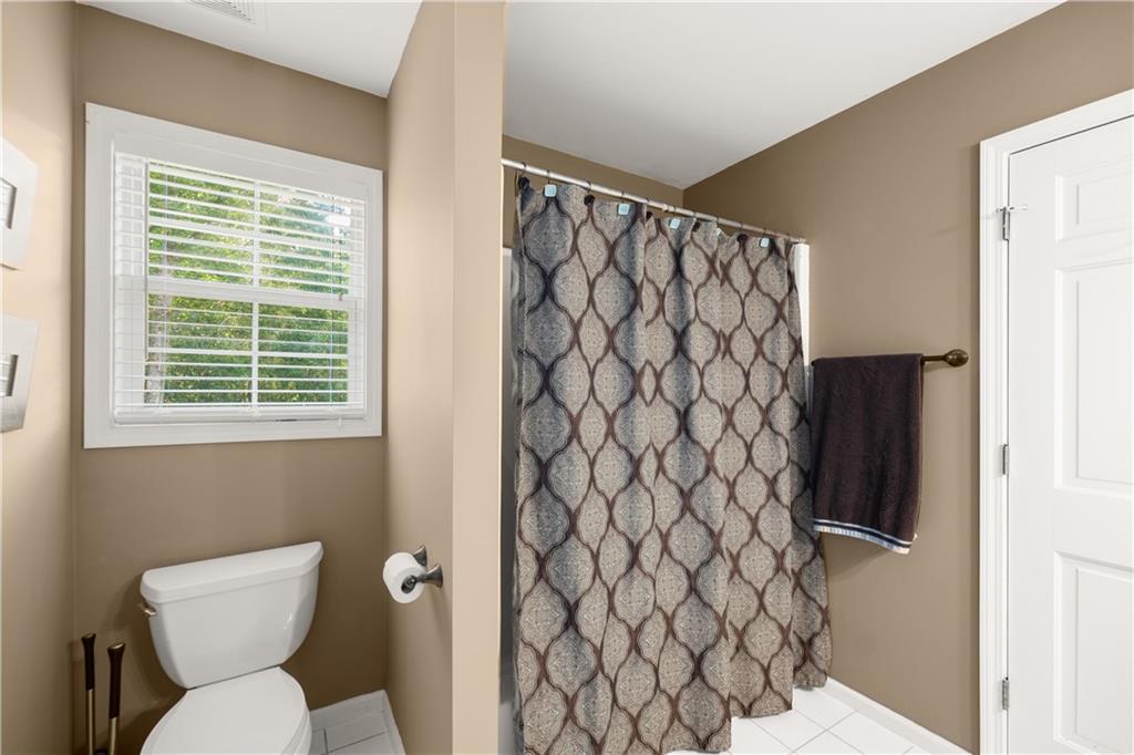 745 Roland Manor Drive Dacula, GA 30019 - Photo 31 of 63 a bathroom with a toilet and a shower curtain