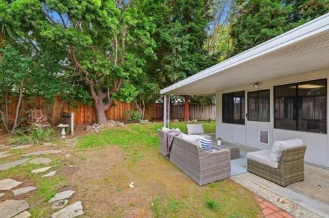 a view of a patio with couches and a table and chairs with plants and trees