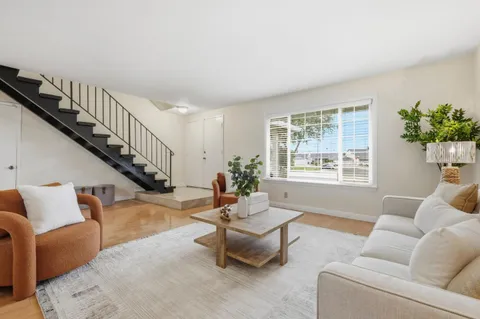 a living room with furniture stairs and a window