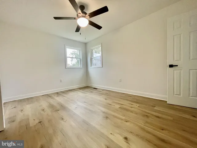 an empty room with wooden floor and ceiling fan