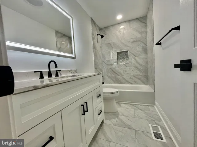 a bathroom with a granite countertop sink a toilet and a bathtub
