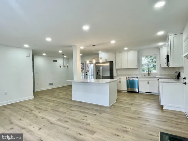 a large kitchen with stainless steel appliances kitchen island a sink dishwasher a refrigerator and a stove with wooden floor