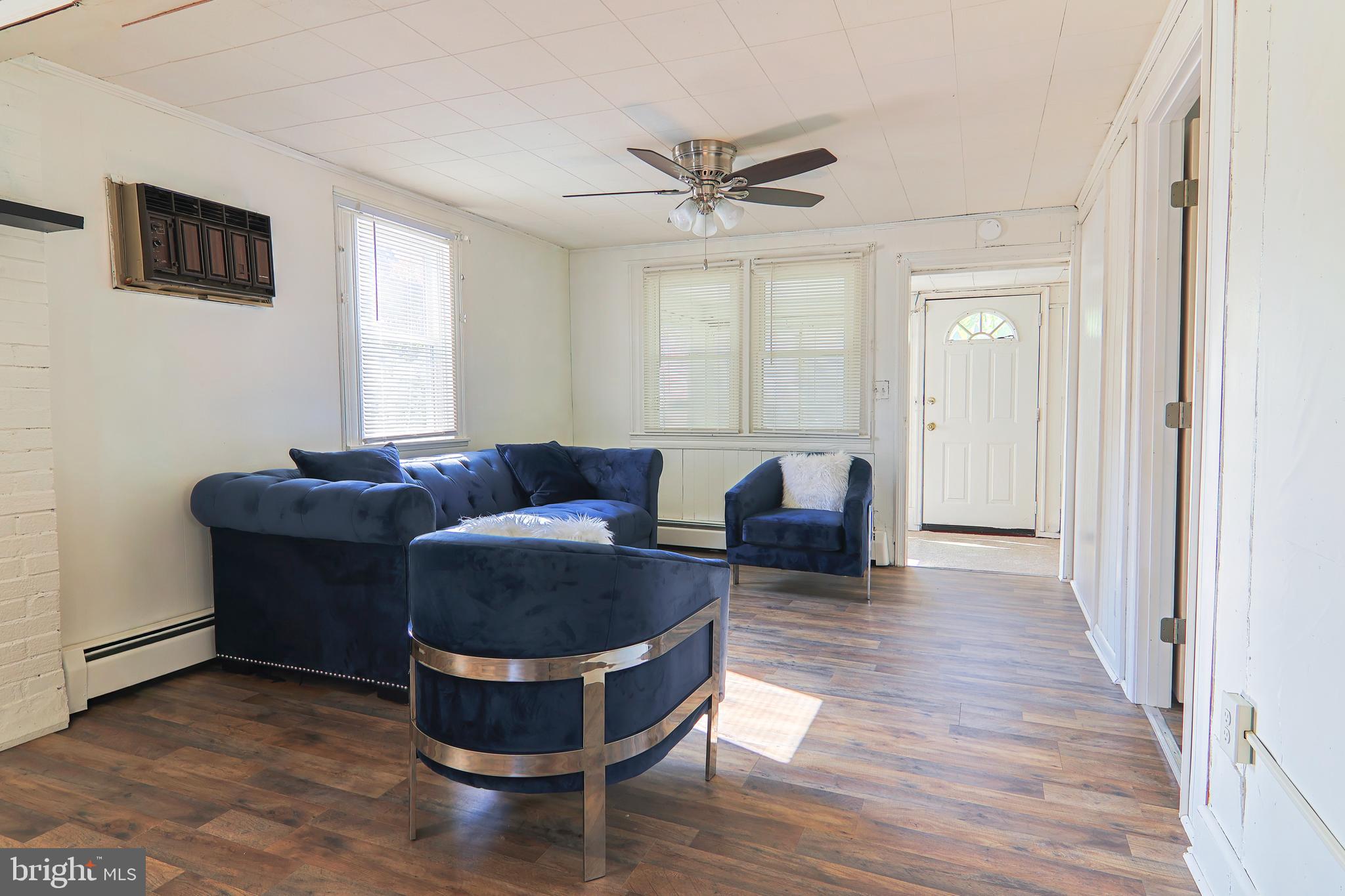 809 Truman Street Cambridge, MD 21613 - Photo 9 of 25 a living room with couches chairs and a potted plant with wooden floor