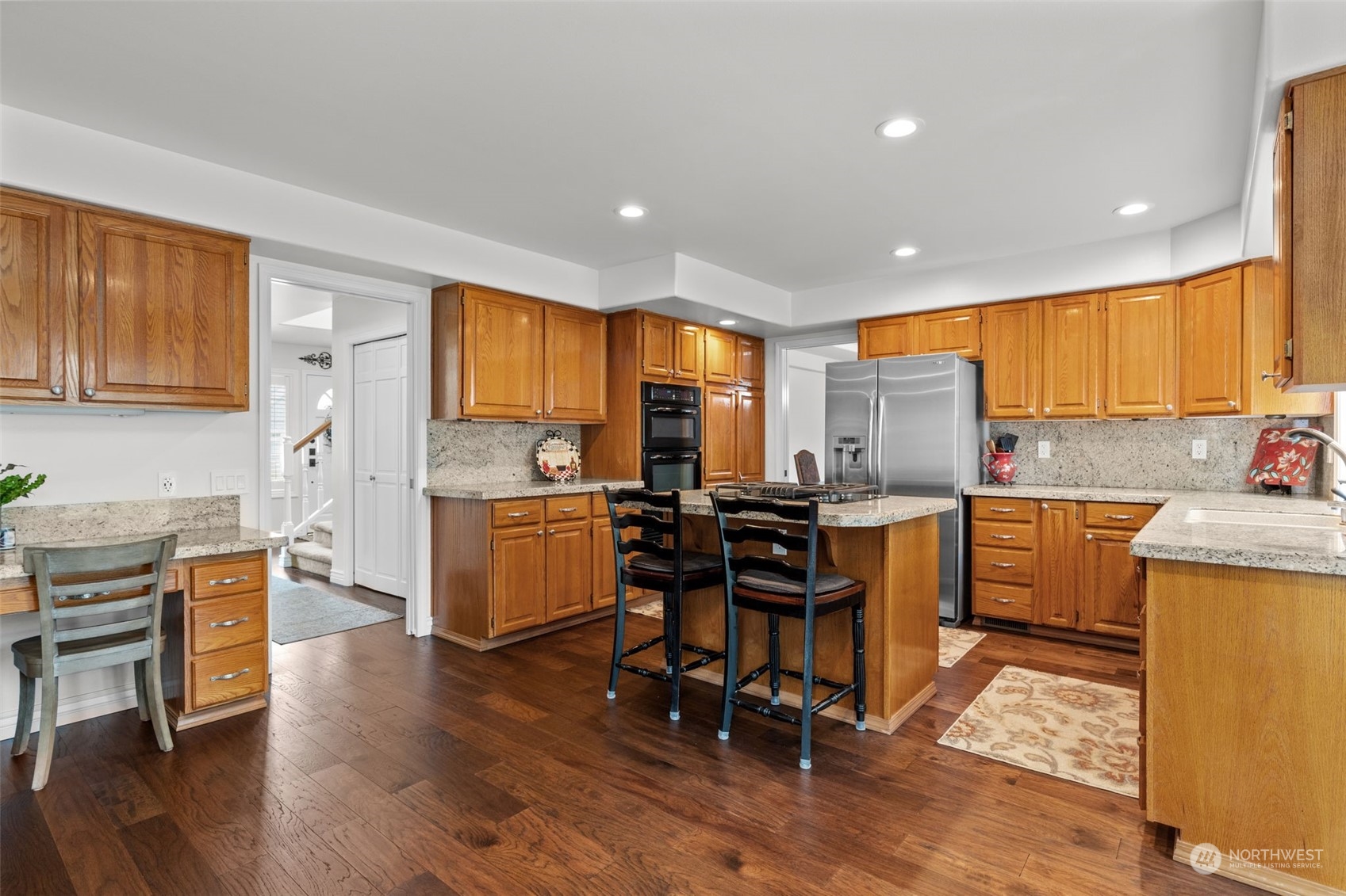 5122 Northeast 17th Street Renton, WA 98059 - Photo 8 of 35 a kitchen with a refrigerator a stove top oven a sink dishwasher and white cabinets with wooden floor
