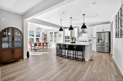 a kitchen with stainless steel appliances a dining table chairs stove refrigerator and cabinets