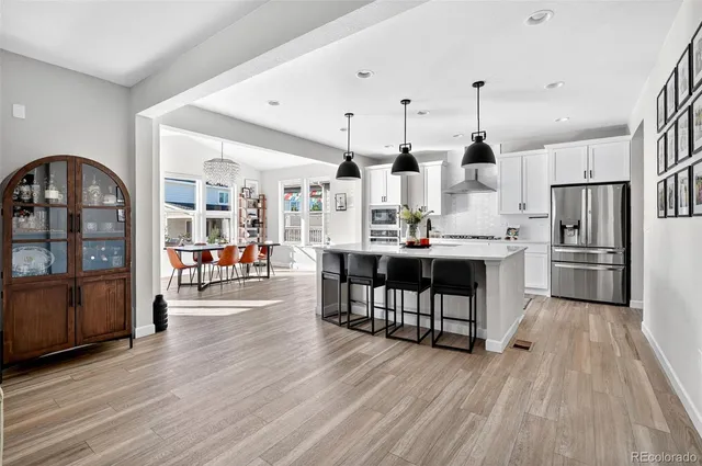 a kitchen with stainless steel appliances a dining table chairs stove refrigerator and cabinets