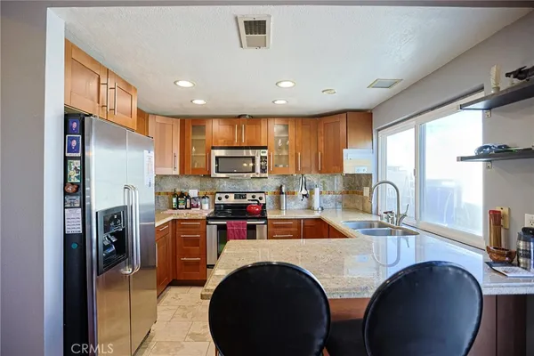 a kitchen with stainless steel appliances a sink a microwave a refrigerator and cabinets