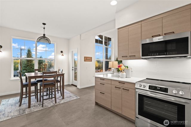 a kitchen with stainless steel appliances a stove a sink dishwasher a microwave oven with cabinets and wooden floor