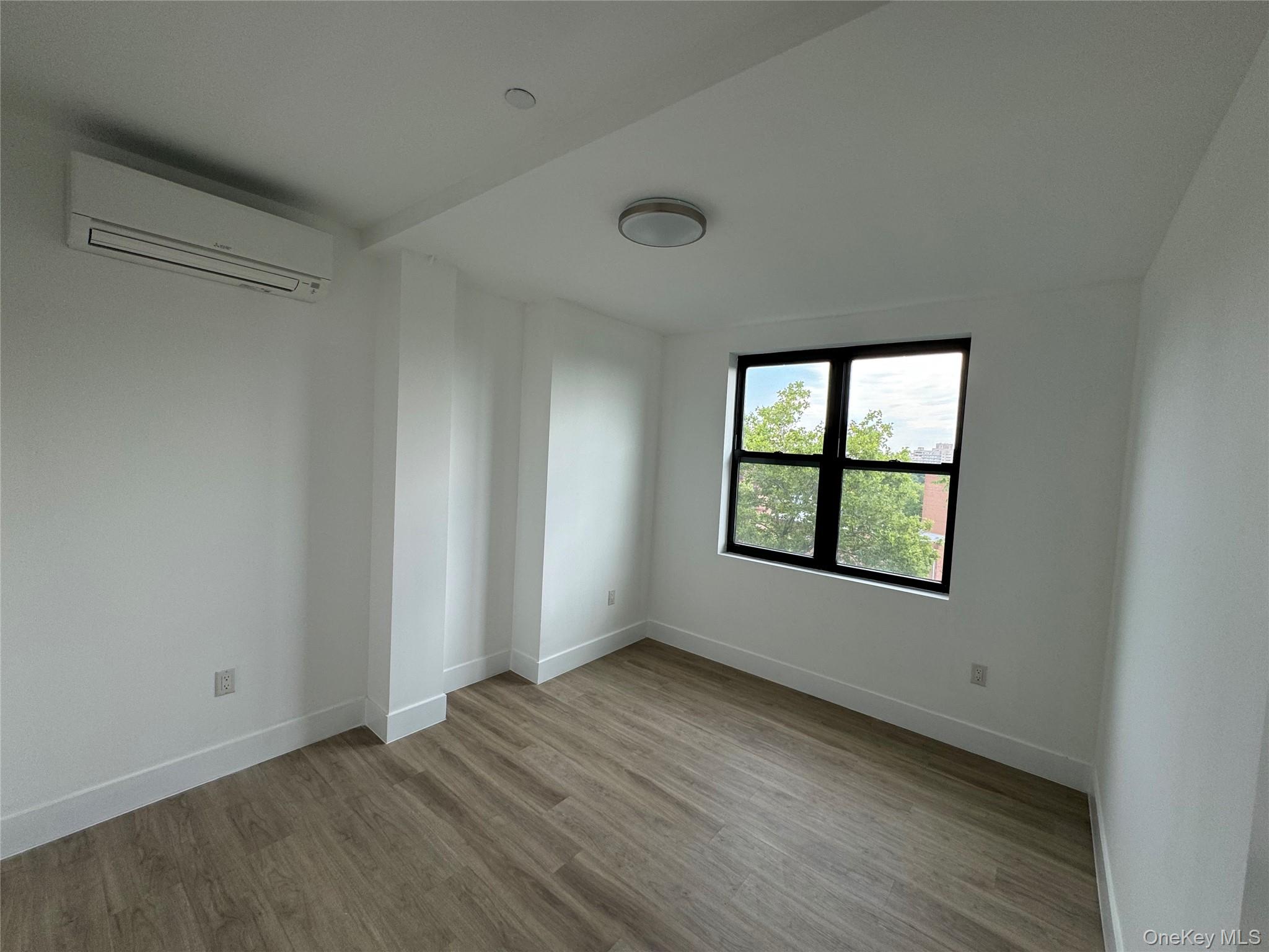 84-03 Lander Street, Unit 2C Queens, NY 11435 - Photo 4 of 7 an empty room with wooden floor and windows
