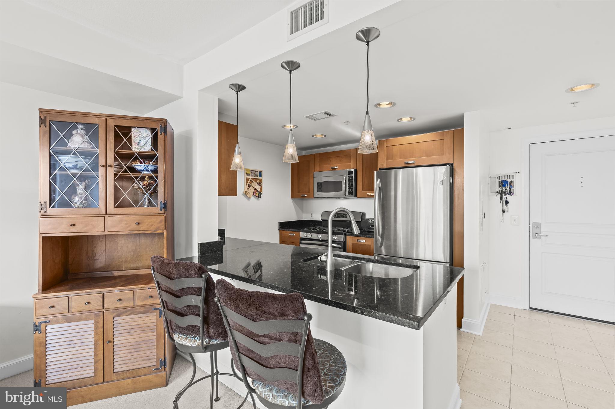 2451 Midtown Avenue, Unit 1413 Alexandria, VA 22303 - Photo 11 of 19 a kitchen with stainless steel appliances granite countertop a refrigerator a stove a sink a dining table and chairs with wooden floor