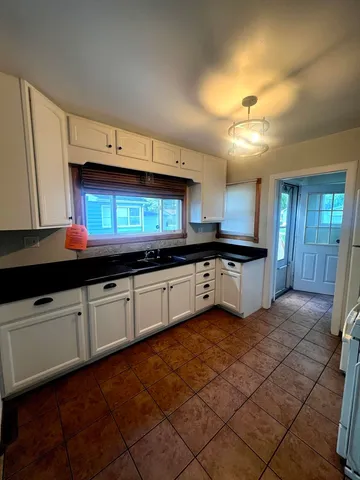 a large kitchen with granite countertop a sink and cabinets