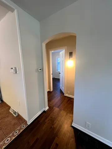 a view of a hallway with wooden floor and a bathroom