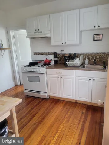 a kitchen with granite countertop wooden floors and white cabinets