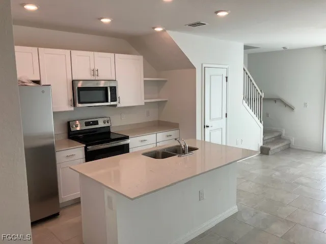 a kitchen with kitchen island a sink appliances and cabinets