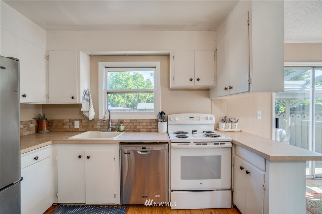 1036 Tyler Street Wenatchee, WA 98801 - Photo 11 of 29 a kitchen with white cabinets appliances a sink and a window