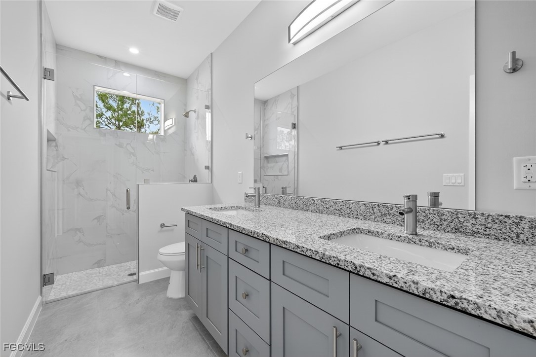 2864 68th Avenue Northeast Naples, FL 34120 - Photo 34 of 47 a bathroom with a granite countertop sink a toilet and shower