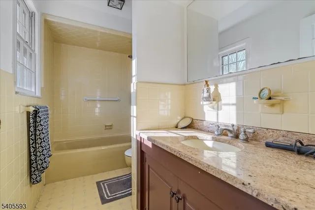 a bathroom with a granite countertop sink a mirror and a bathtub