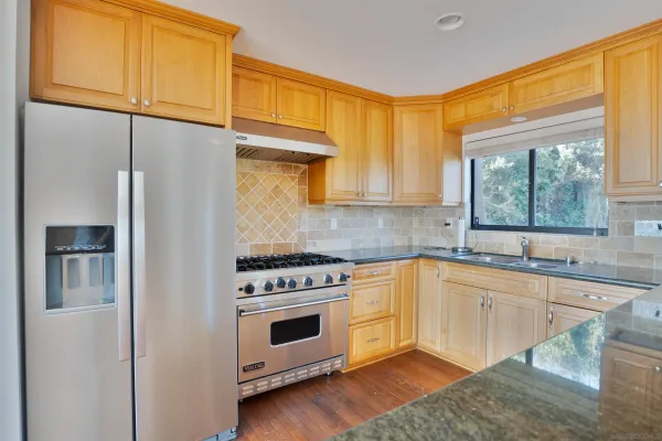 a kitchen with granite countertop a stove a sink and a refrigerator