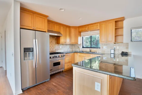 a kitchen with stainless steel appliances granite countertop a refrigerator a sink dishwasher a stove with wooden cabinets and floor