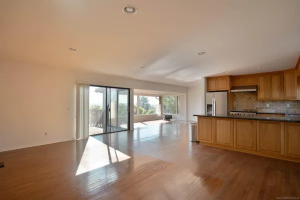 a open kitchen with granite countertop a stove top oven a sink and white cabinets with wooden floor